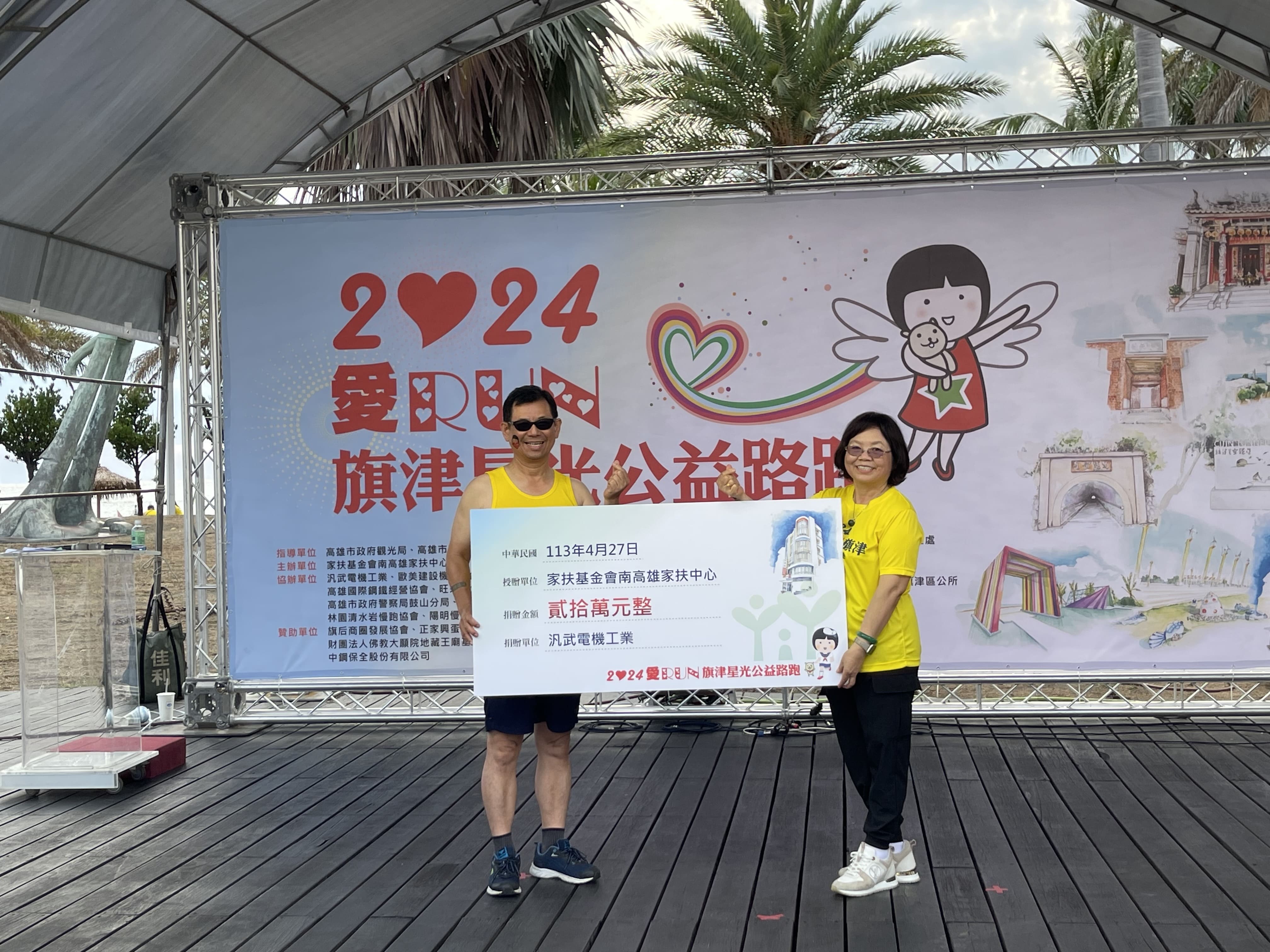 兩位穿黃色衣服的人正在舉行支票捐贈儀式